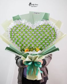 a person holding a bouquet of flowers in front of a heart shaped box with the words love written on it