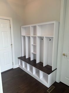 an empty room with white shelves and wood flooring on the side walk in closet