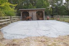 two horses are standing in their stalls at the stable, with gravel on the ground