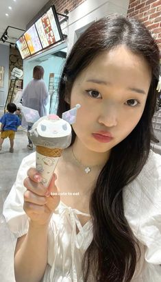 a woman holding an ice cream cone in her right hand and looking at the camera