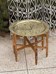 a table with a glass top sitting in front of a wrought iron fence and shrubbery