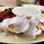 the plate is full of eggs, bacon, and other breakfast foods with sauce on it