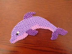 a purple dolphin made out of legos on a wooden table