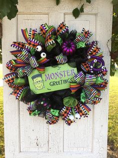 a halloween wreath with green and purple decorations on the front door to a house that says monstide greetings