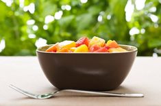 two bowls filled with fruit sitting on top of a table next to a fork and knife