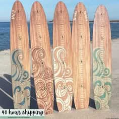 four wooden surfboards lined up next to the ocean