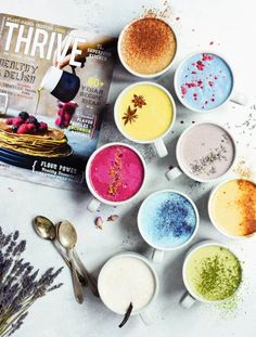 there are many different colors of powder in cups and spoons on the table next to each other