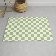 a green and white checkered rug on the floor next to a basket with a plant in it