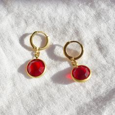 These earrings feature 10mm siam ruby red vintage stones attached to gold plated 11mm hoops. Red 14k Gold Pierced Earrings, Single Ruby Earring In Red, Red Ruby Single Earring, Elegant Small Hoop Red Earrings, Elegant Red Round Hoop Earrings, Red Elegant Round Hoop Earrings, Red Huggie Earrings Gift, Red Huggie Earrings For Gift, Elegant Red Hoop Jewelry