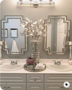 a bathroom with two sinks, mirrors and flowers in a vase on the counter top