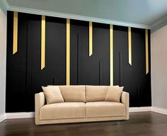 a couch sitting in front of a black wall with gold strips on it's sides