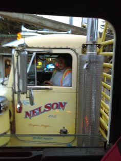 a man sitting in the driver's seat of a yellow truck with nelson written on it