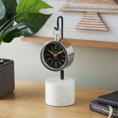 an alarm clock sitting on top of a wooden table next to a potted plant