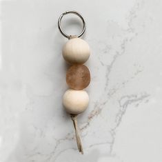 three wooden beads hanging from a metal ring on a marble surface with a keychain