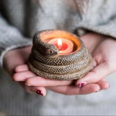 a woman holding a small candle in her hands