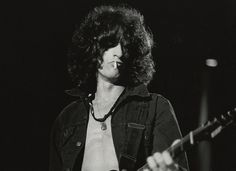 a black and white photo of a person playing a guitar in front of a microphone