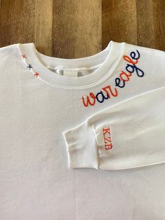 a white long sleeved shirt with the word happy on it and stars embroidered across the chest