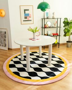 a white table sitting on top of a black and white rug in a living room