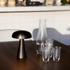 several glasses and vases on a table in a kitchen