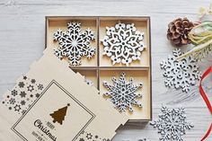 wooden ornaments in a box with ribbon on the table next to it and other decorations