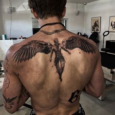 the back of a man's upper body with an angel tattoo on it