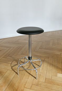 a black stool sitting on top of a hard wood floor