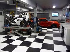 a motorcycle on a lift in a garage with two cars behind it and a tv mounted to the wall