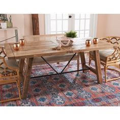 a wooden table with chairs around it on a colorful rug in front of a window