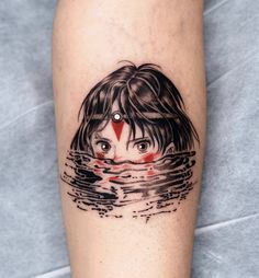 a woman's leg with a black and white tattoo on it, which has a red triangle in the water