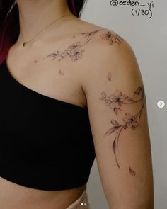 a woman wearing a black top with flowers on her arm and chest tattoo design by ceden y