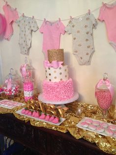 a table topped with pink and gold baby shower items on top of a wooden table