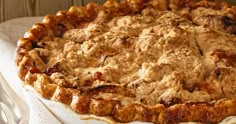 a pie sitting on top of a white plate covered in crumbly toppings