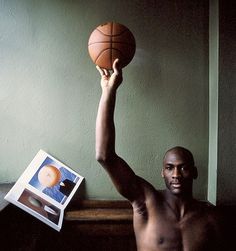 a shirtless man holding a basketball in his right hand and an album on the left