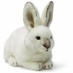 a white stuffed rabbit sitting on top of a white floor and looking at the camera