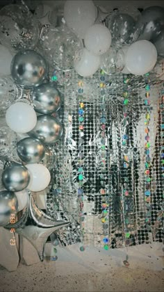 silver and white balloons are hanging on the wall next to a mirror with some disco balls