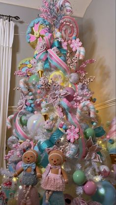 a pink and blue christmas tree decorated with balloons, ornaments and other items in pastel colors