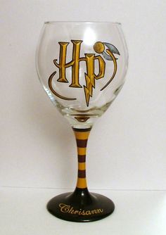 a wine glass with the word harry potter painted on it's side and an image of a hogwarts symbol