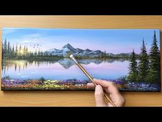 a person is holding a paintbrush and painting a landscape