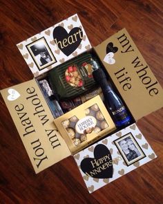 a wine bottle and some chocolates in a box on a wooden table with two signs