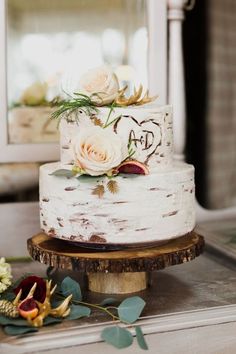 a white wedding cake with flowers on the top is sitting on a table next to a mirror