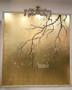 a large gold painting with white flowers on it's side and a chandelier hanging from the ceiling