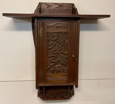 a wooden clock with carvings on the front and back sides, hanging from a wall