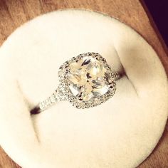 an oval shaped diamond ring on top of a white cushion