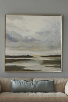 a painting hanging on the wall above a couch in a living room with gray walls