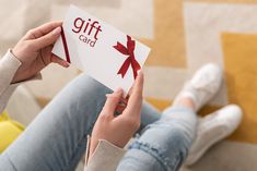 a woman is holding up a gift card