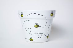 a white cup with bees painted on the outside and inside, sitting in front of a white background