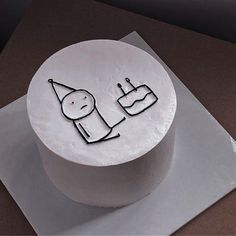 a white cake with black writing on it sitting on top of a piece of paper