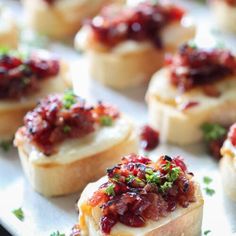 small appetizers with cranberry toppings on a white platter, ready to be eaten