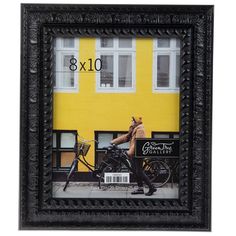 a framed photograph of a man on a bike in front of a yellow building with the number 10x10