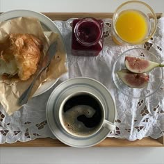 a breakfast tray with coffee, fruit and croissants